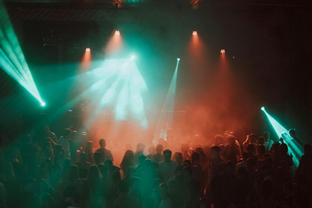 Crowd dancing under colorful stage lights at a live music performance